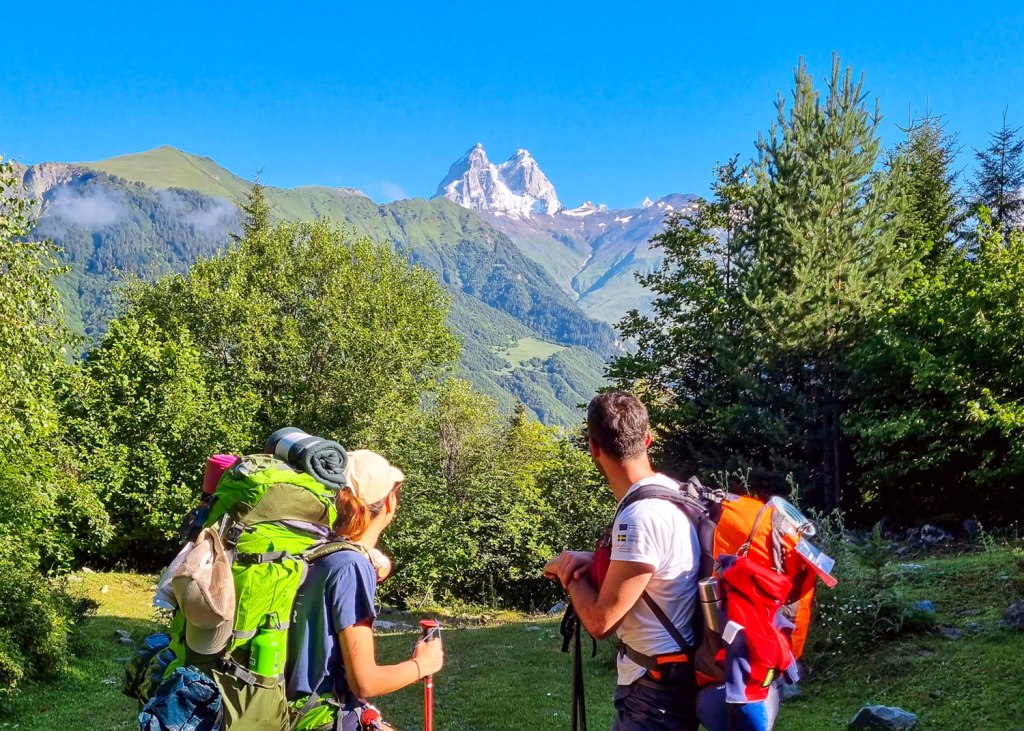 Two hikers looking Ushba mountain. Highlander Adventure, Biliki App