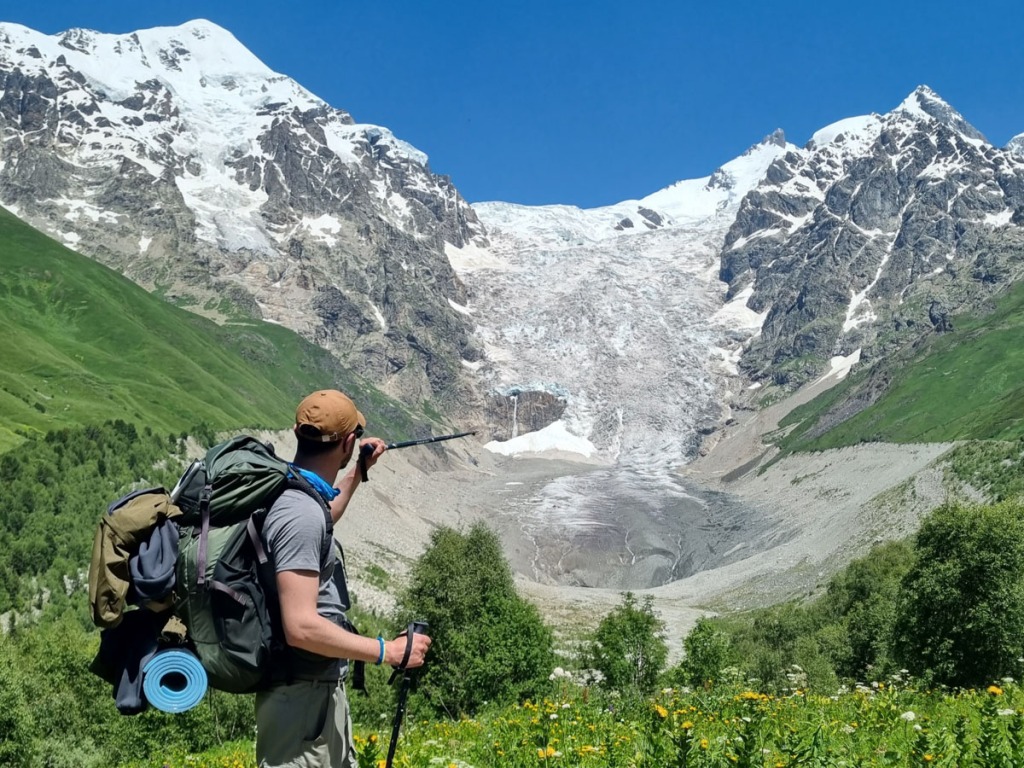 A hiker point on Adishi glacier. Beautiful view of mountain and glacier. Highlander Adventure, Biliki App